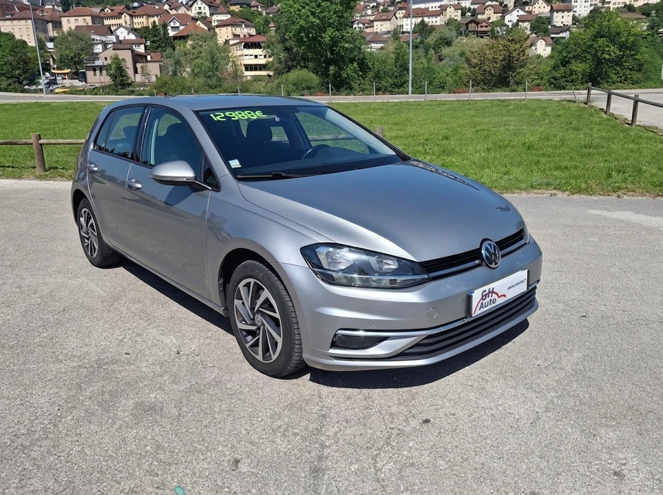 Véhicule d'occasion exposé sur un parking, étiquette de prix 12 988€ visible sur le pare-brise